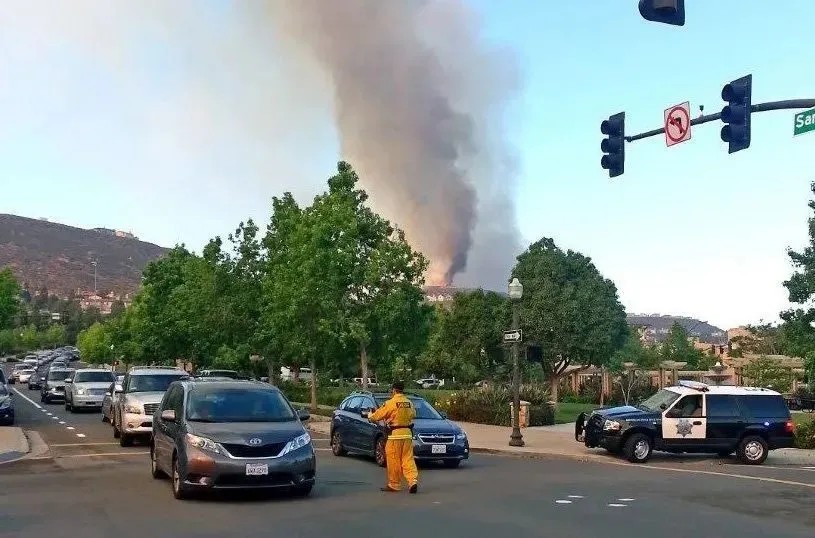 Cars backed up at an intersection during a fire evacuation, with a firefighter directing traffic