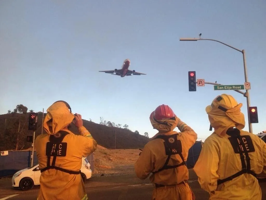 Firefighters at a San Elijo Road intersection watching an aircraft pass overhead